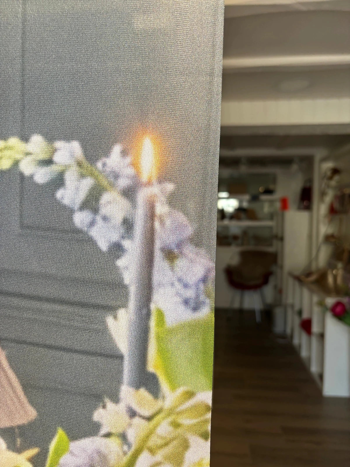 Bannière décorative Vitrines Fanchon à motif floral — bougie et glycines blanches imprimées sur tissu gris, exposée dans une boutique de décoration en arrière-plan