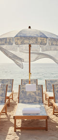 Banner décoratif Plage & transat - Trois transats en bois avec parasol motif toile de Jouy bleu et blanc sur plage de sable fin face à la mer