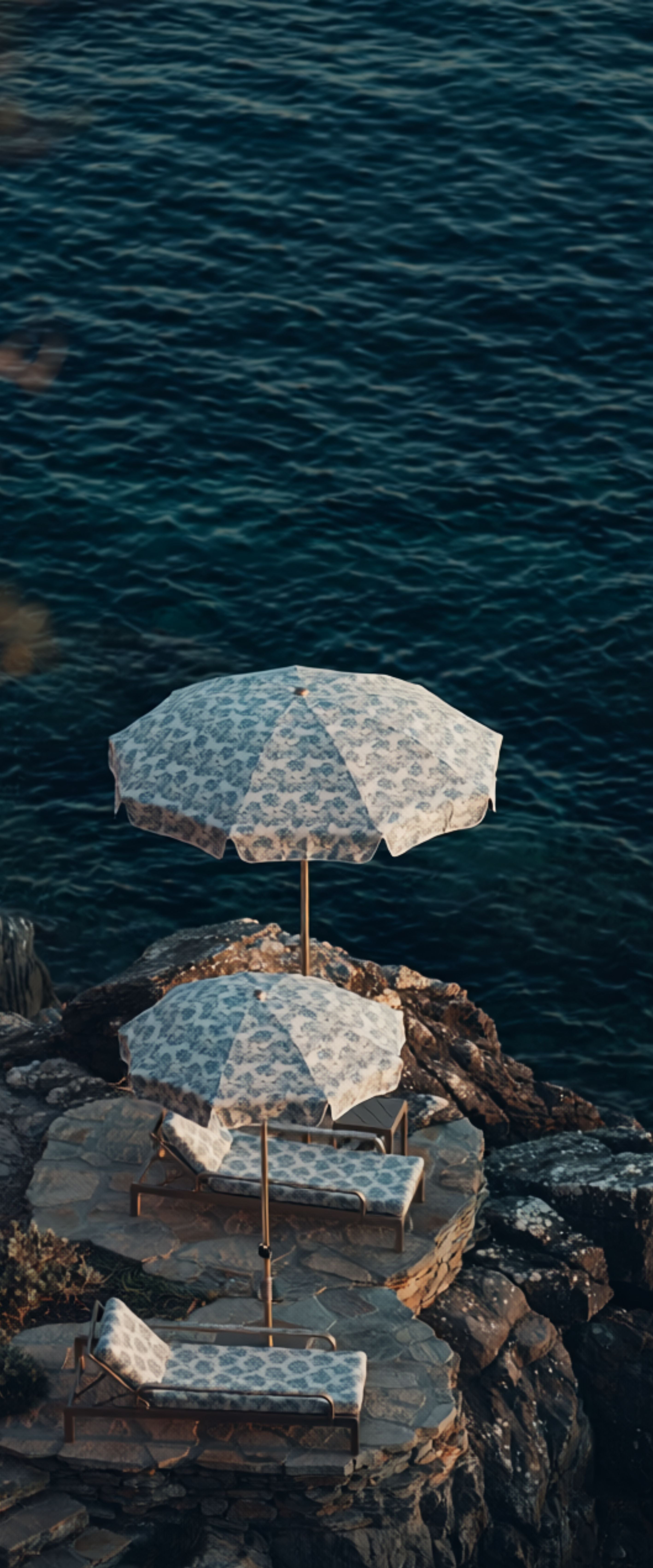 Banner décoratif Rivage - Transats blancs avec parasols géométriques bleu et blanc sur rochers face à la mer, ambiance méditerranéenne