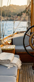 Banner décoratif Sunset sailing - Voilier classique en bois avec pont en teck et voile beige, vue sur la côte italienne au coucher de soleil