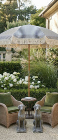 Banner décoratif Tea time - Parasol rayé bleu et blanc avec statues de lévriers, fauteuils en rotin et hortensias blancs, ambiance jardin anglais
